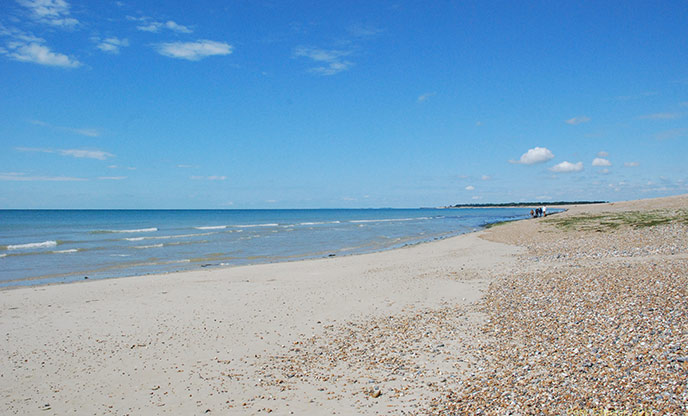 A bank of pebbles and sand leading to calm turquoise waters at Littlehampton West