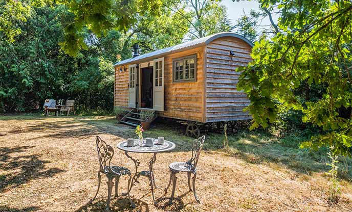 Rustic wooden shepherd's hut situated amongst trees in Sussex