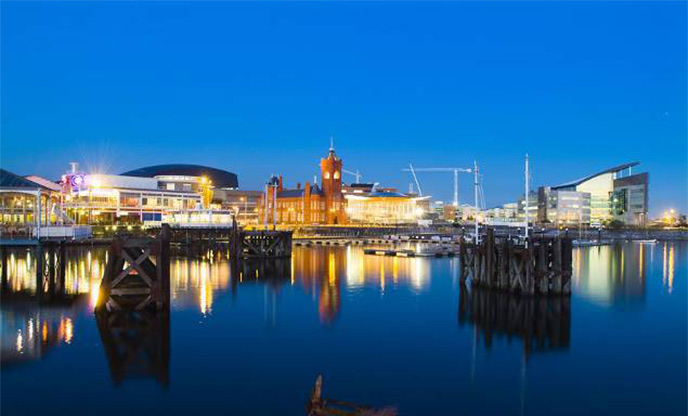 Vibrant Cardiff Bay at night as city lights reflect off the water